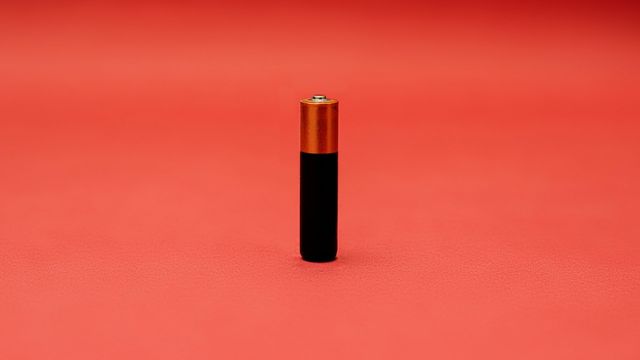 An orange and black battery on a red background. 