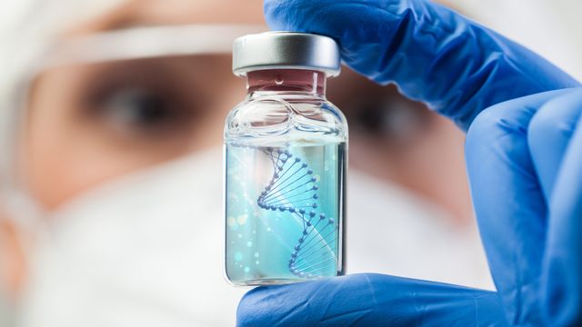 A scientist holding up a glass vial. 