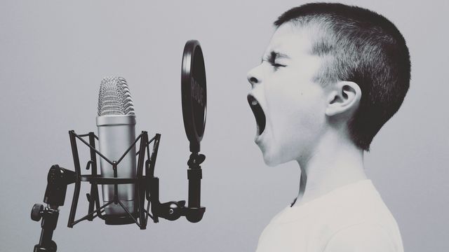 A boy shouting into a microphone. 