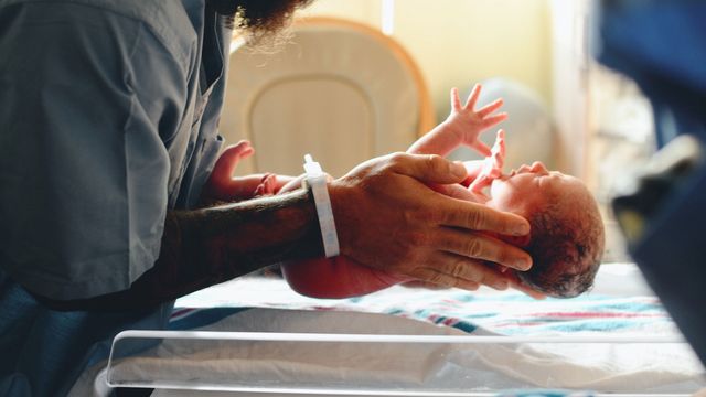 A newborn baby is held. 