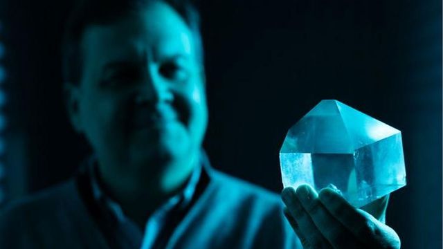 A researcher presents a crystal to the camera. 