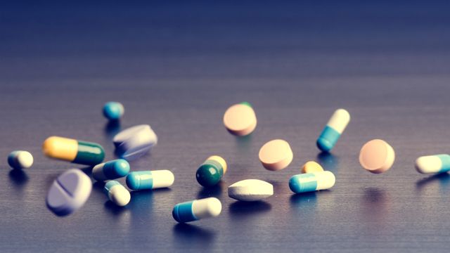 Various oral medicines falling onto a tabletop. 